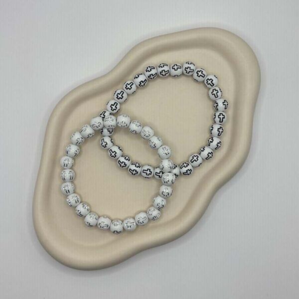 Zwei weiße Perlenarmbänder mit Kreuzperlen dekorativ arrangiert