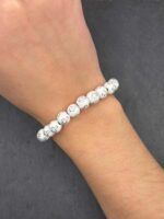 Schlichtes Perlenarmband aus weißen Kreuzperlen am Handgelenk getragen