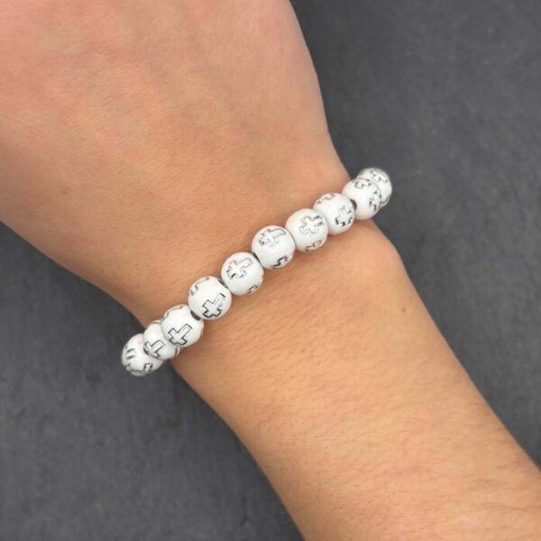 Schlichtes Perlenarmband aus weißen Kreuzperlen am Handgelenk getragen