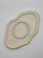 Weißes Perlenarmband mit Kreuzperlen auf organischer Ablage