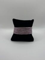 Stretch-Armband in Violett und Silber – funkelndes Strassarmband mit Glitzersteinen, elastisch und anschmiegsam, präsentiert auf schwarzem Kissen.