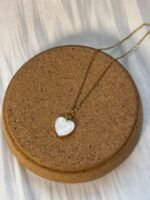 Schlichte Damenkette mit Herzanhänger, dekorativ auf runder Korkplatte präsentiert
