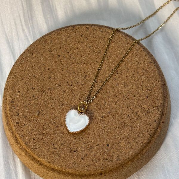 Schlichte Damenkette mit Herzanhänger, dekorativ auf runder Korkplatte präsentiert