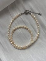 Zart gedrehte Damen-Perlenkette aus natürlichen Süßwasserperlen mit silbernem Verschluss – stilvolles Accessoire mit leichtem Glanz auf weißem Satin