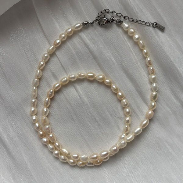 Zart gedrehte Damen-Perlenkette aus natürlichen Süßwasserperlen mit silbernem Verschluss – stilvolles Accessoire mit leichtem Glanz auf weißem Satin