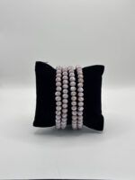 Five strands of pale pink faceted bead bracelets resting on a black display pillow