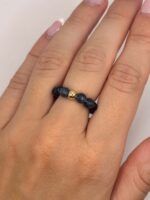 Close-up of a hand wearing a black bead bracelet with a gold spacer bead and pink manicured nails.